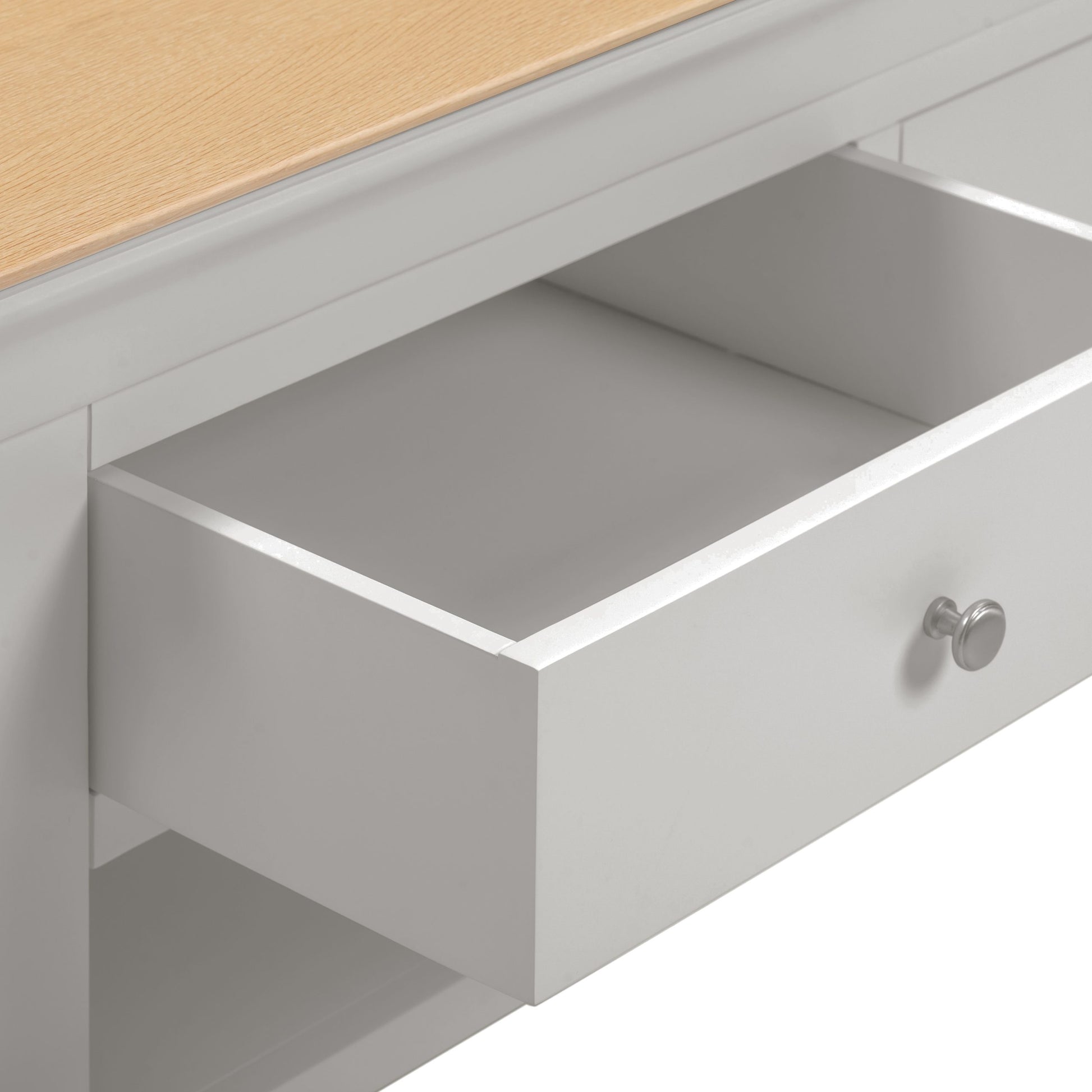 Open drawer of a piece of furniture with a light wood top.