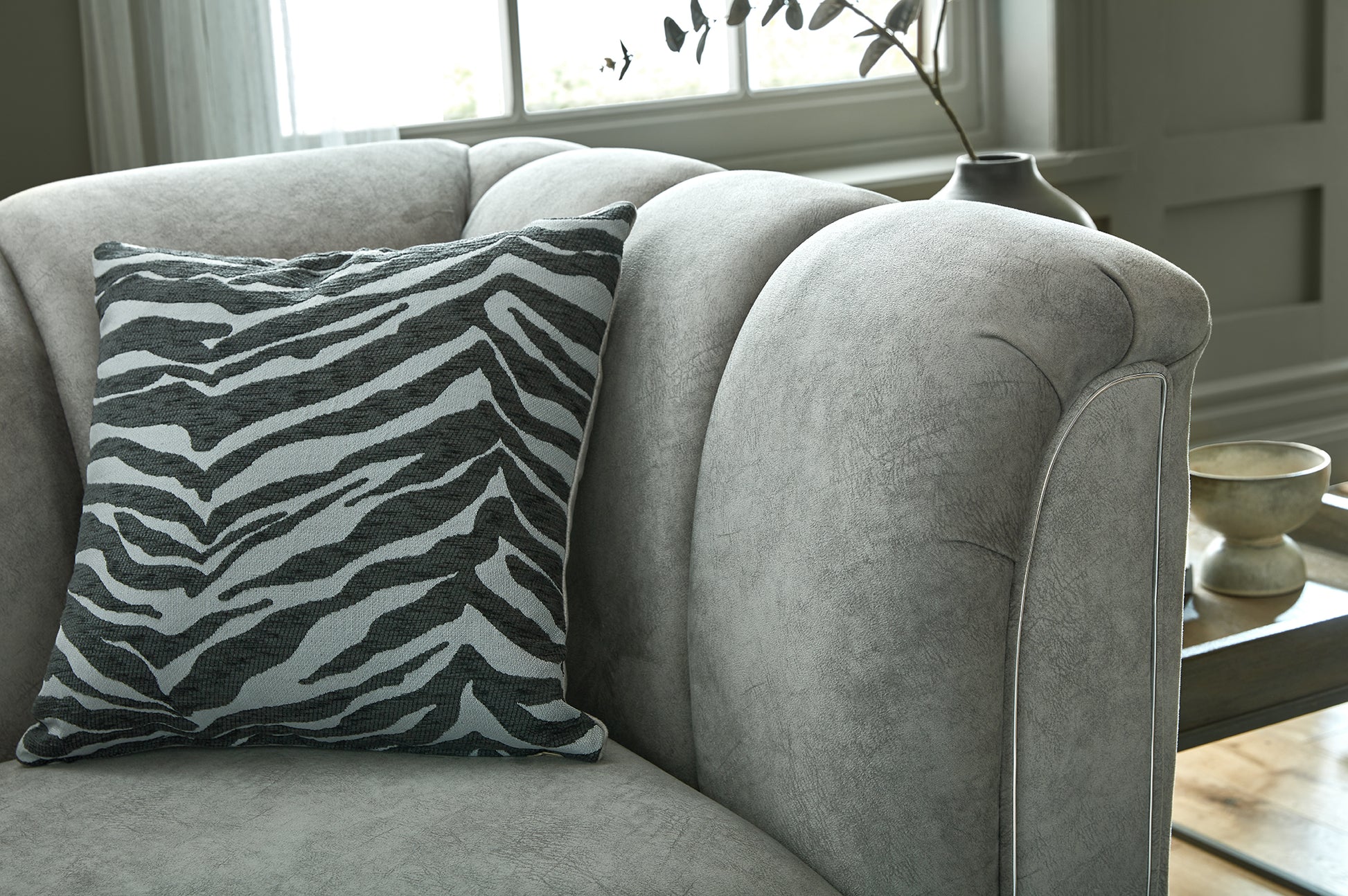 Gray sofa with a zebra-patterned pillow in a room setting.