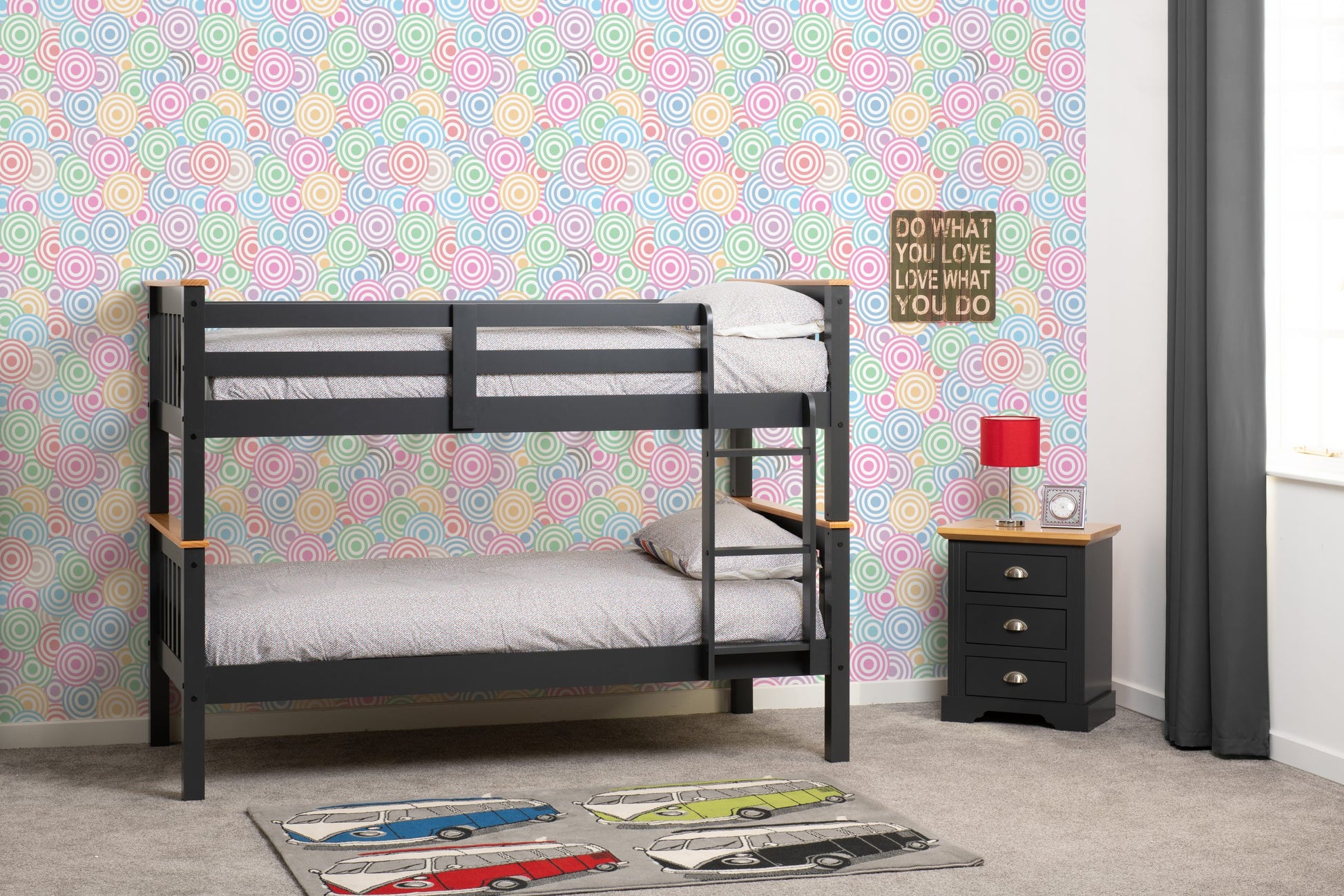 Grey bunk bed in a room with colorful circular patterned wallpaper.
