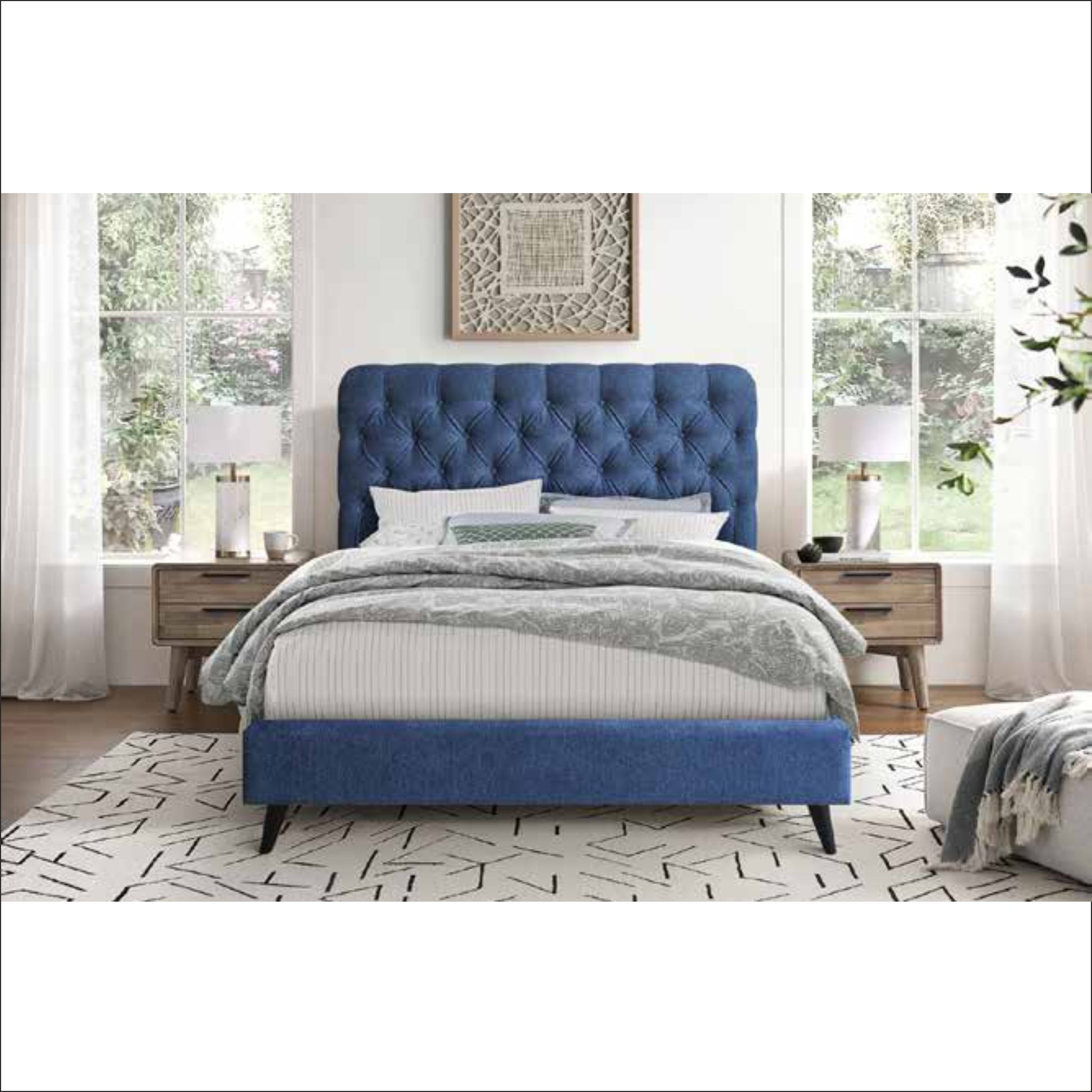 Blue upholstered bed in a bedroom setting with white walls and large windows.