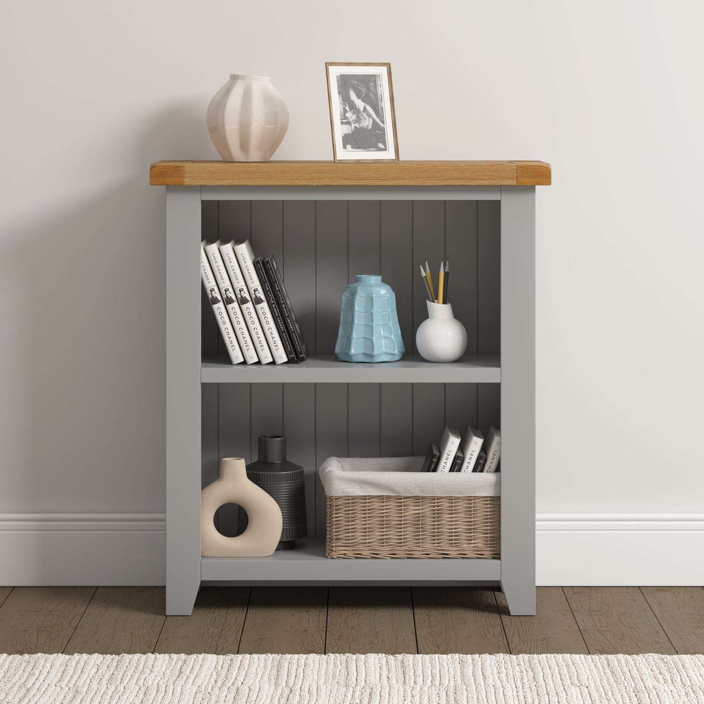 Bookshelf with wooden top and gray base, displaying books, vases, and a basket.