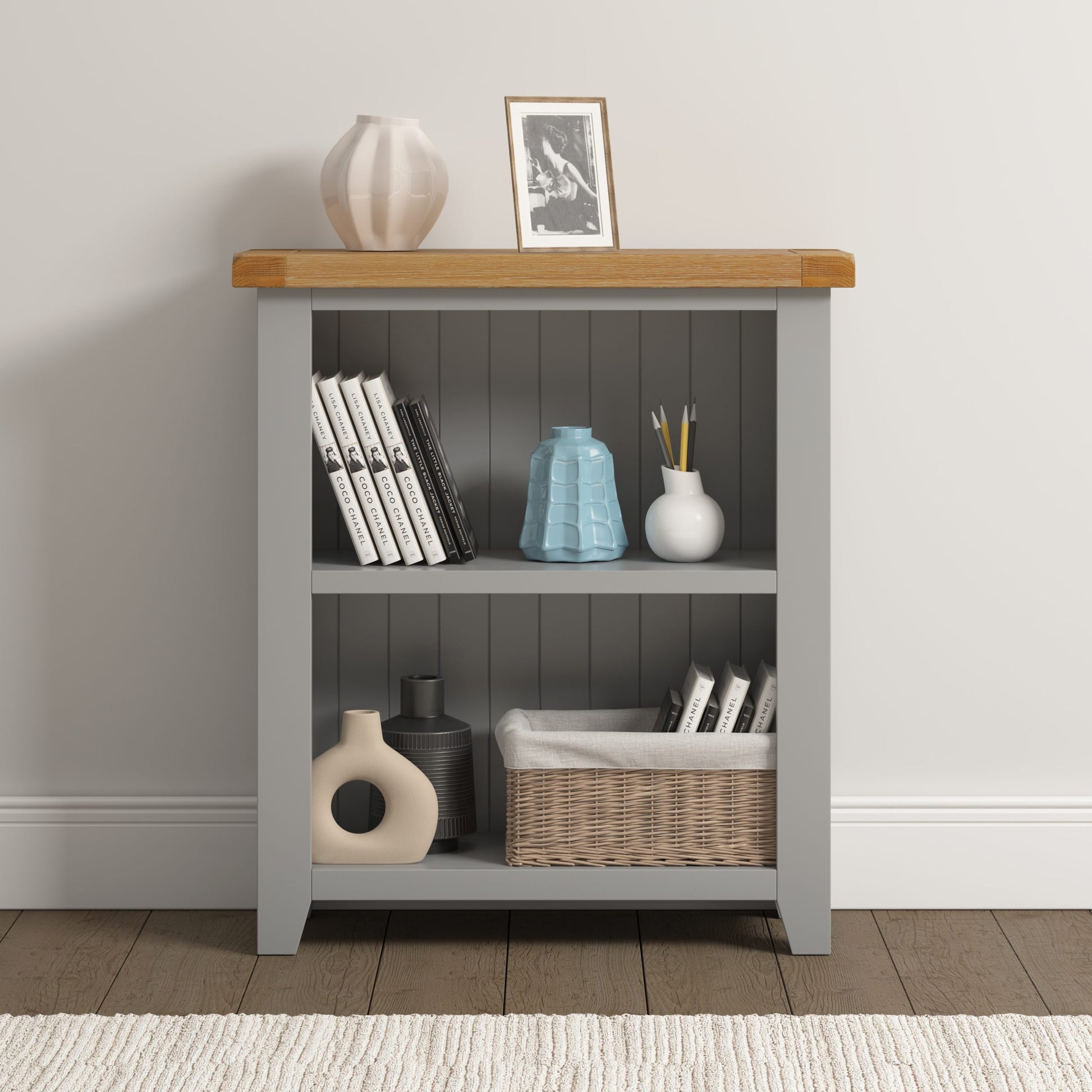 Bookshelf with wooden top and gray base, displaying books, vases, and a basket.