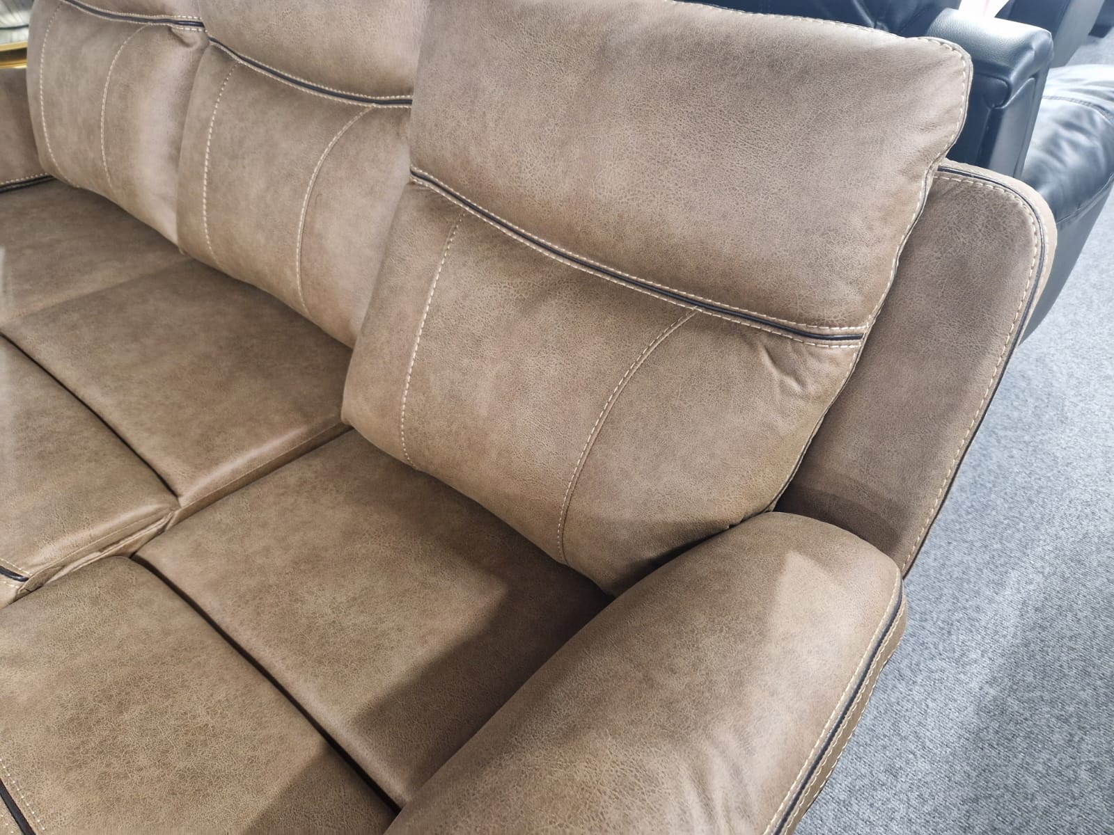 Tan Brown sectional recliner corner sofa with visible stitching on a carpeted floor.