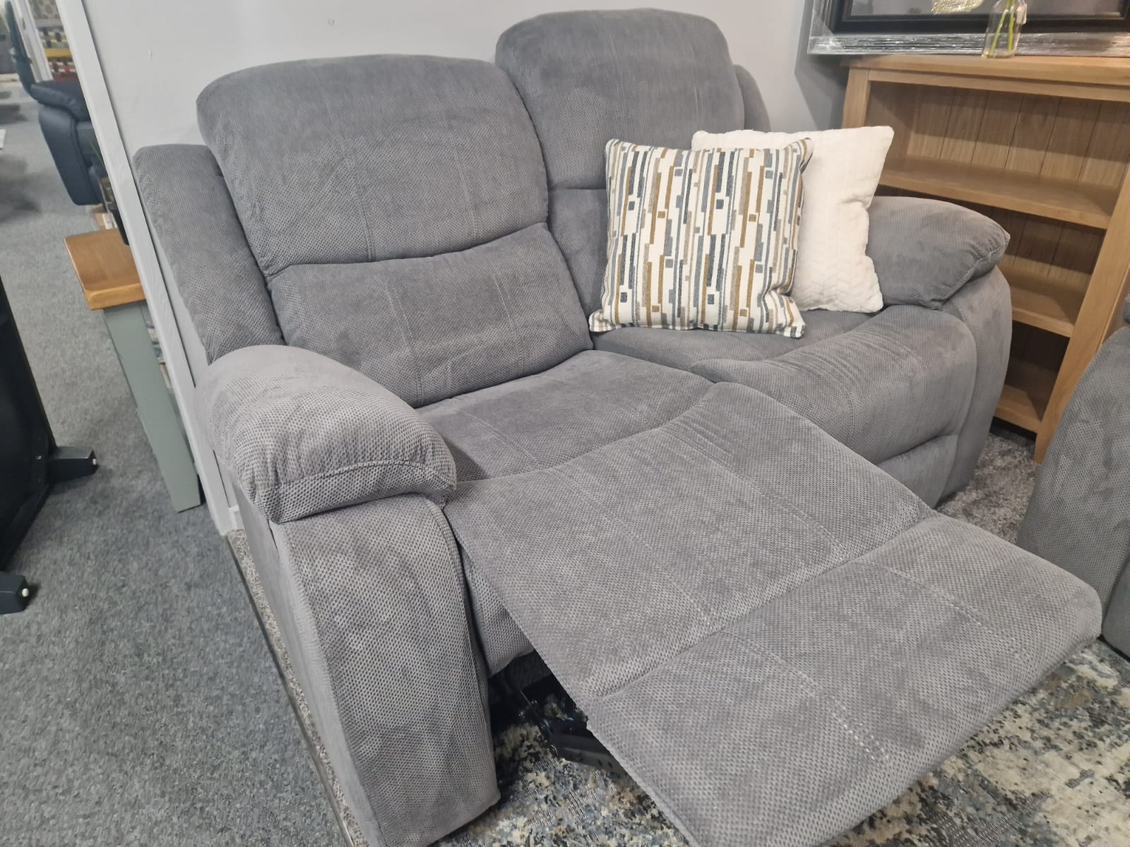 Grey fabric reclining sofa set with cushions in a showroom setting