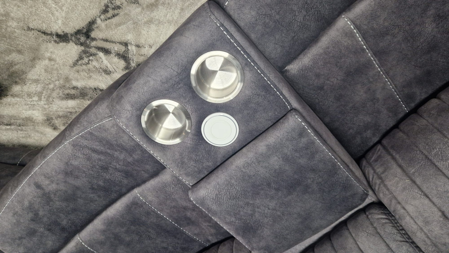 Close-up of a Dark Gray Fabric sectional reclining corner sofa with chrome cupholders in a centre consoles on a textured surface.
