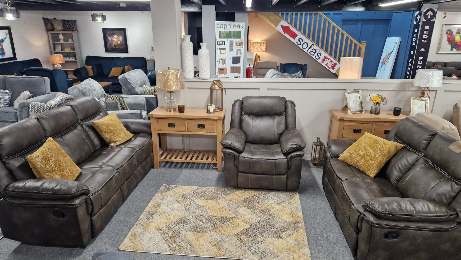 Living room with gray sofas, armchairs, and a rug in a furniture store.