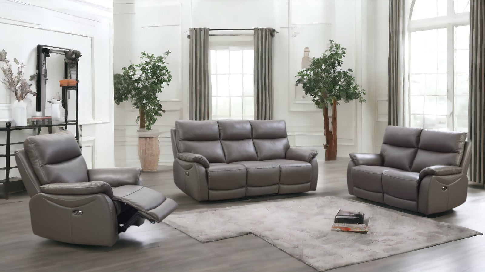 Gray leather reclining sofa set in a modern living room with large windows and plants.