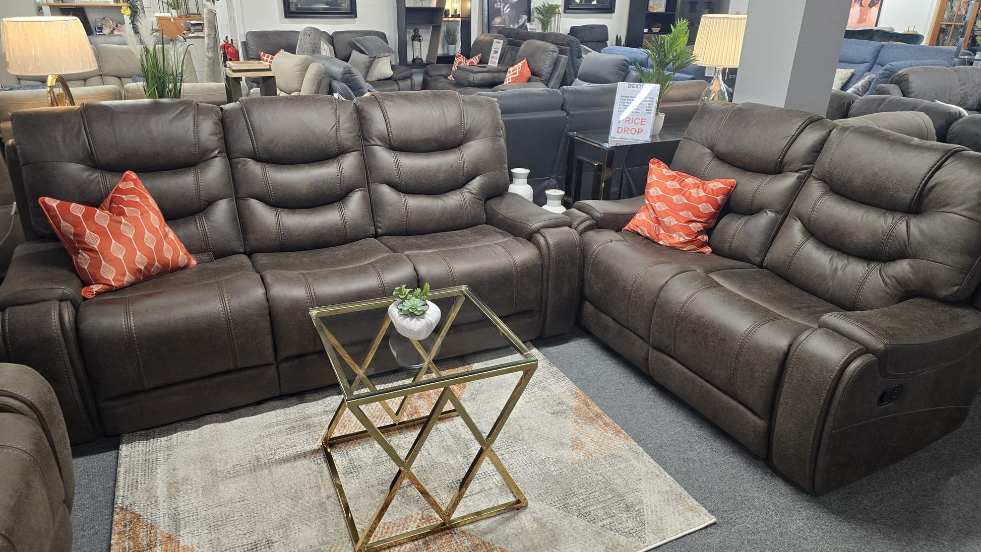 Brown Fabric recliner sofa with orange pillows in a showroom setting.