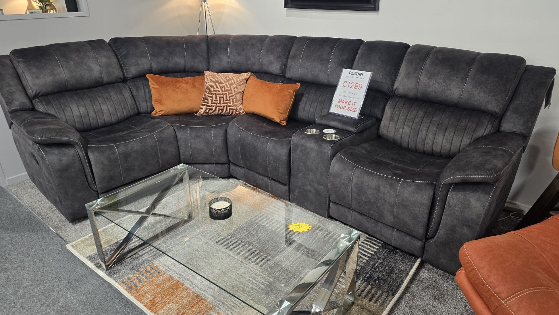 Dark Gray Fabric sectional reclining corner sofa with orange and brown cushions in a living room setting.