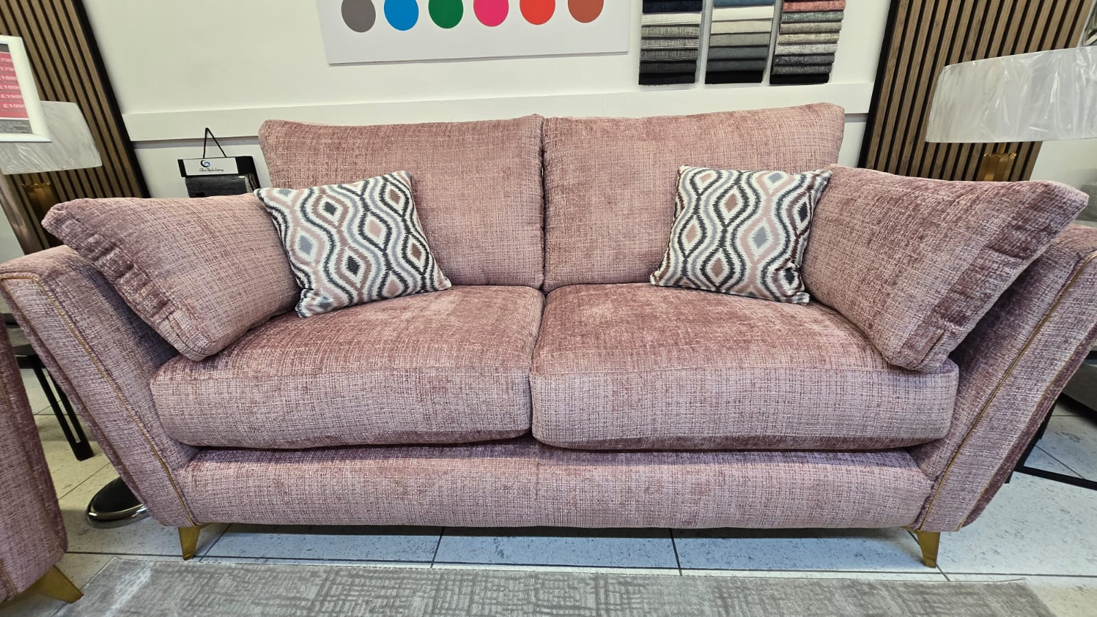 pink fabric sofas with patterned cushions in a showroom.