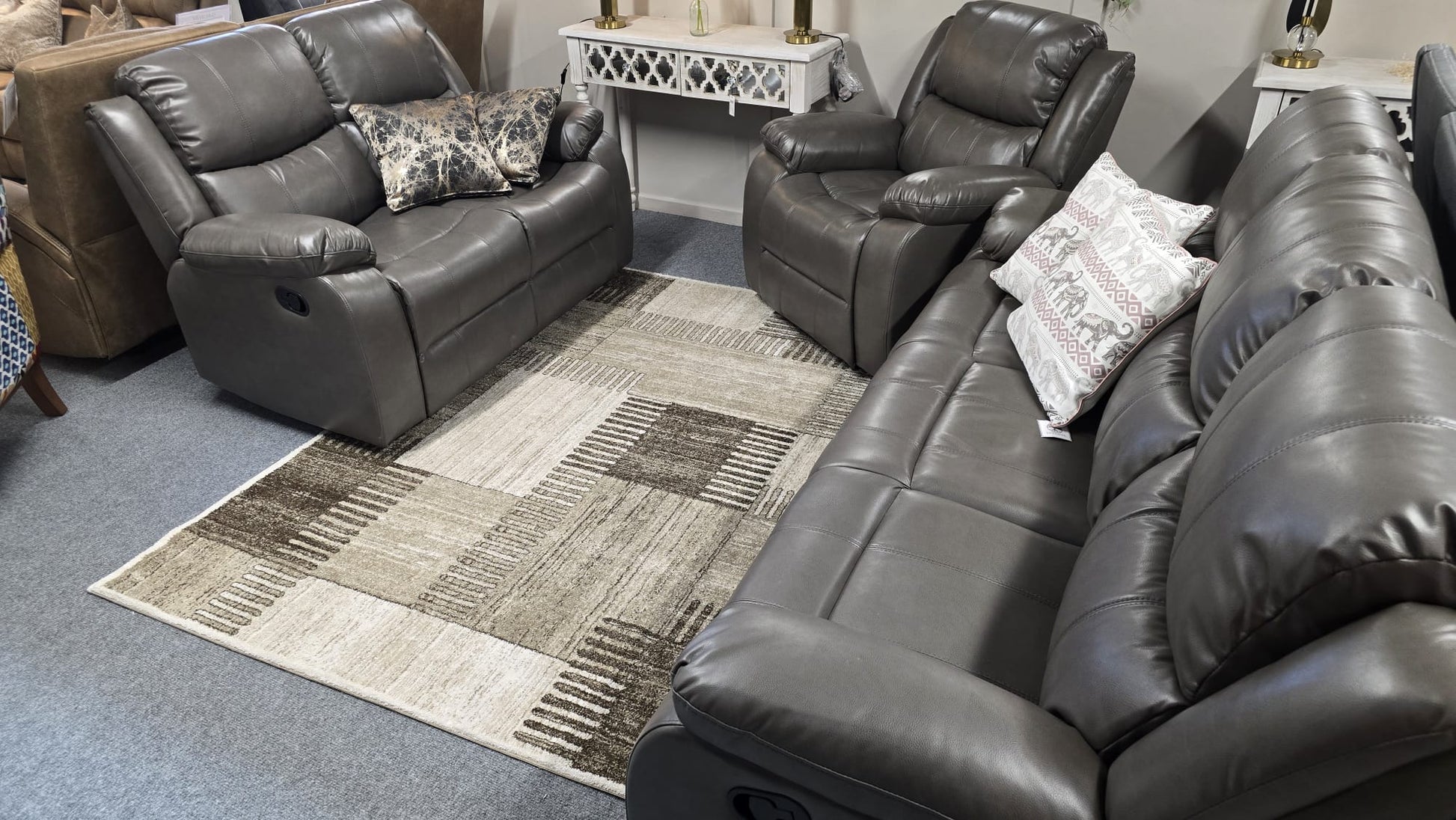Gray leather recliner sofa set in a living room setting with a patterned rug.