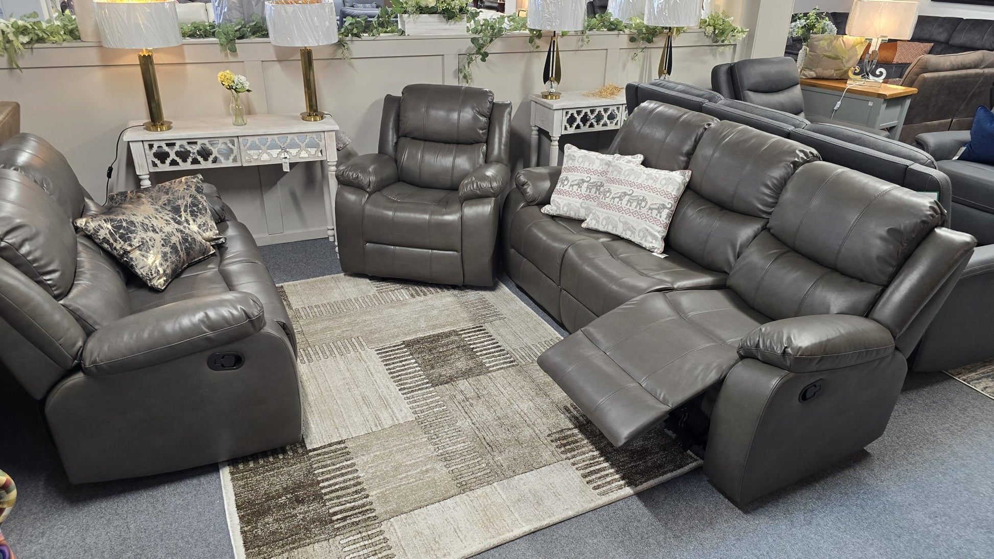 Gray reclining sofa set in a showroom with decorative elements.
