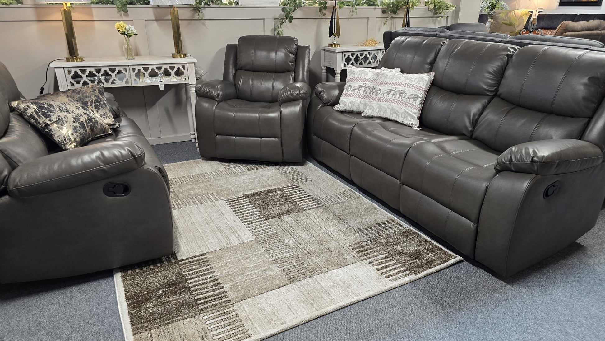 Gray leather recliner sofa set in a living room setting with decorative pillows and a rug.