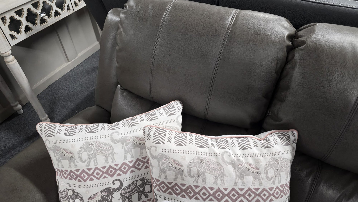 Gray leather sofa with patterned cushions featuring elephants on a neutral background