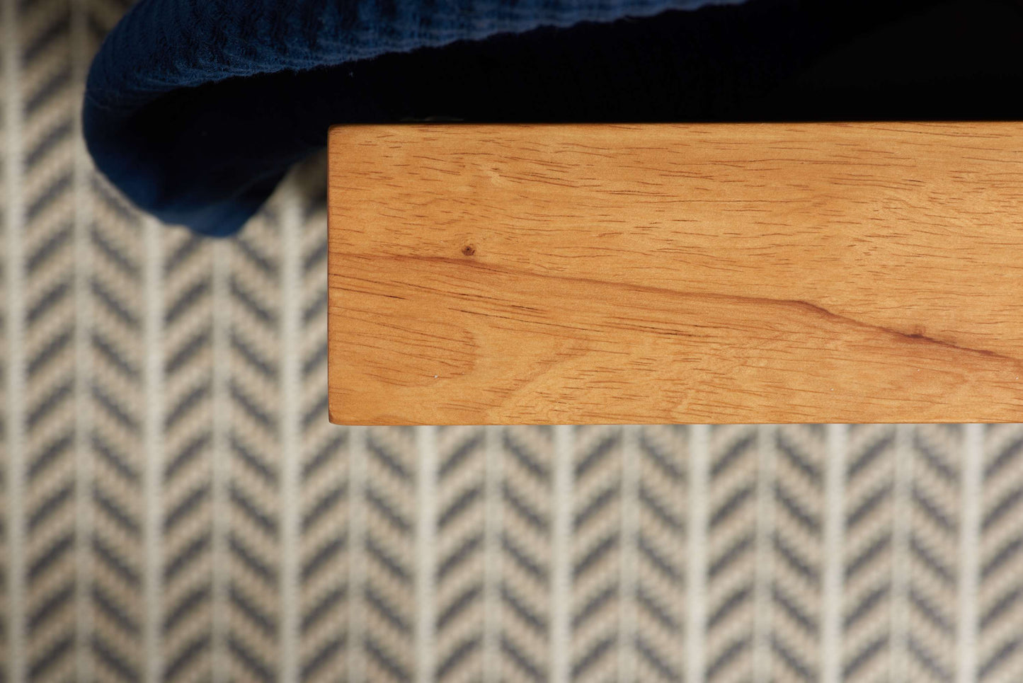 Close-up of a wooden surface with a blue fabric corner on a patterned rug