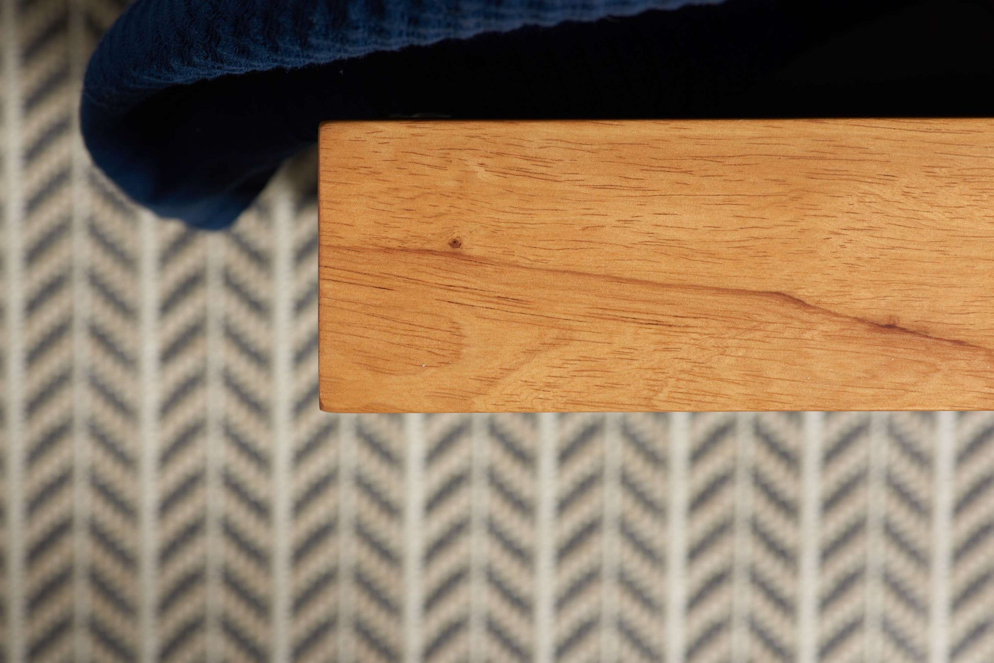 Close-up of a wooden surface with a blue fabric corner on a patterned rug