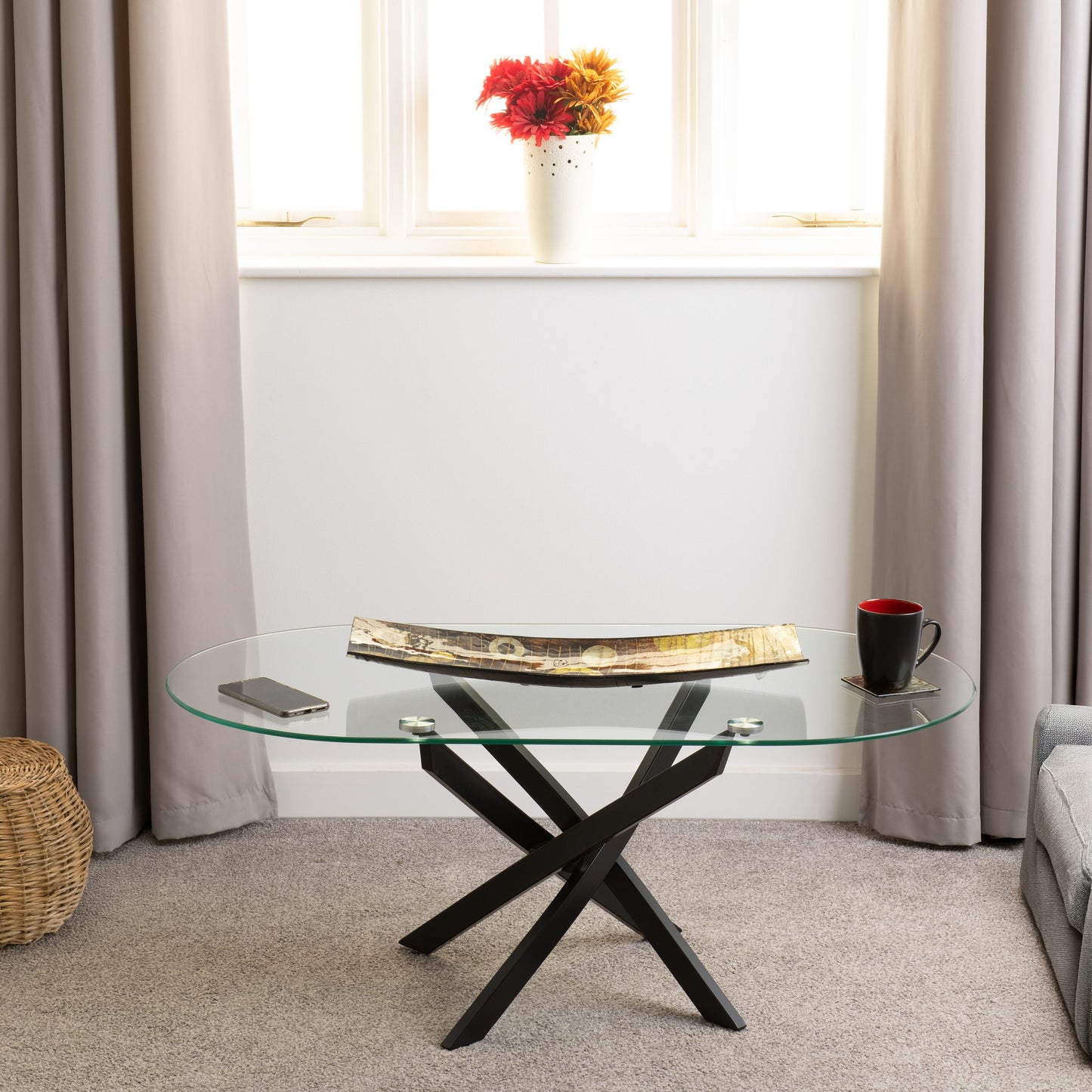 Glass coffee table with black metal legs in a living room setting.